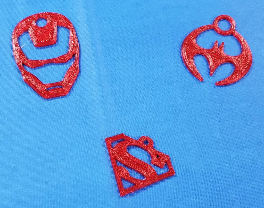 Red superhero symbol keychain tags made on a 3-D printer.